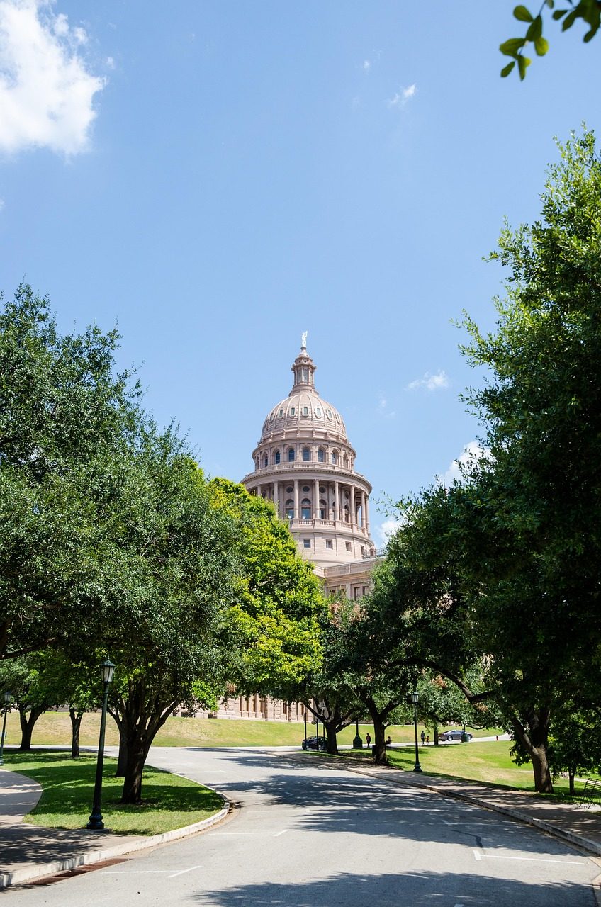 The Texas State Capitol framed by live oaks in downtown Austin